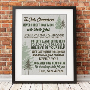 May include: A framed print with a white background and brown text that reads "To Our Grandson Never Forget How Much We Love You" and includes a message about following your dreams and believing in yourself. The print features a green and brown forest design.