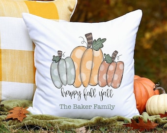 May include: White pillow with a design of three pumpkins in different colors and sizes. The pumpkins have white polka dots. The text "happy fall y'all" and "The Baker Family" is printed below the pumpkins.