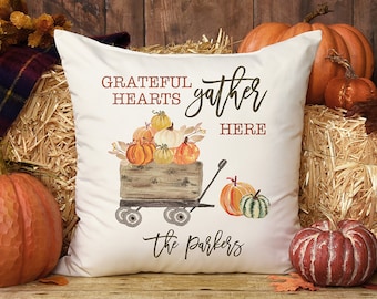 May include: White throw pillow with the text "Grateful Hearts gather here" and a watercolor illustration of a wagon filled with pumpkins. The text "The Parkers" is at the bottom of the pillow.