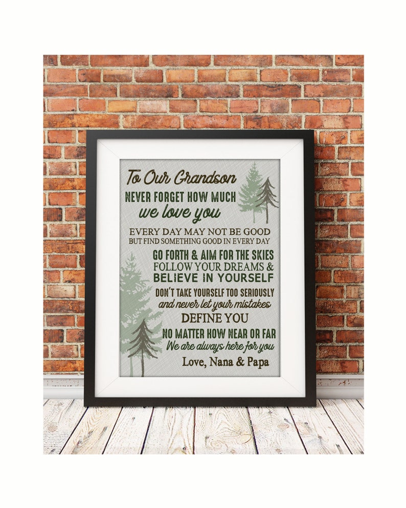 May include: A framed print with a light gray background and green trees. The print features a message to a grandson, encouraging him to follow his dreams and believe in himself. The text reads: "To Our Grandson Never Forget How Much We Love You Every Day May Not Be Good But Find Something Good In Every Day Go Forth & Aim For The Skies Follow Your Dreams & Believe In Yourself Don't Take Yourself Too Seriously And Never Let Your Mistakes Define You No Matter How Near Or Far We Are Always Here For You Love, Nana & Papa"