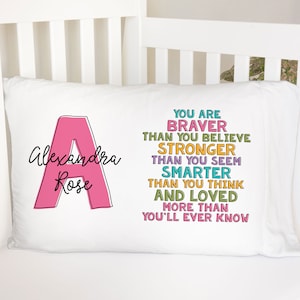May include: A white pillow with the letter "A" in pink and the text "Alexandra Rose" in black. The pillow also has the text "You are braver than you believe, stronger than you seem, smarter than you think, and loved more than you'll ever know" in colorful text.