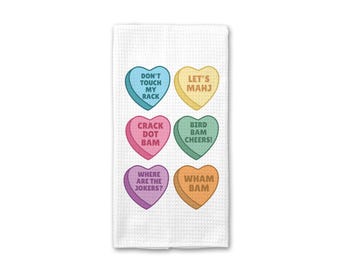 Puede incluir: Toalla de cocina blanca con seis caramelos en forma de corazón de colores. Cada caramelo tiene una frase única: "DON'T TOUCH MY RACK", "LET'S MAHJ", "CRACK DOT BAM", "BIRD BAM CHEERS!", "WHERE ARE THE JOKERS?" y "WHAM BAM".