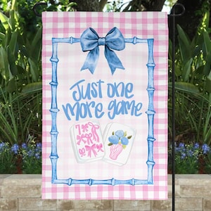 May include: A pink and white checkered garden flag with a blue bamboo-style frame and bow. The flag features the text "Just one more game" in blue script, along with illustrations of game pieces. Perfect for outdoor decor.