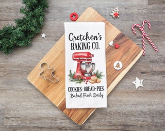Pode incluir: Toalha de cozinha branca com uma batedeira de pé vermelha e prateada, bagas vermelhas e o texto "Gretchen's Baking Co. Cookies - Bread - Pies Baked Fresh Daily".