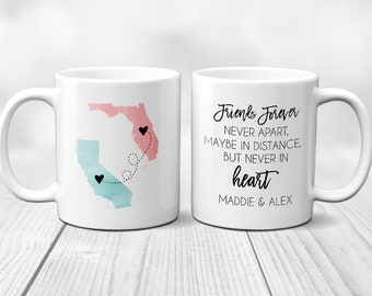 May include: Two white coffee mugs with a design of the states of California and Florida. The mugs are connected by a dotted line with hearts at each end. One mug has the text "Friends Forever Never Apart, Maybe in Distance, But Never in Heart Maddie & Alex".