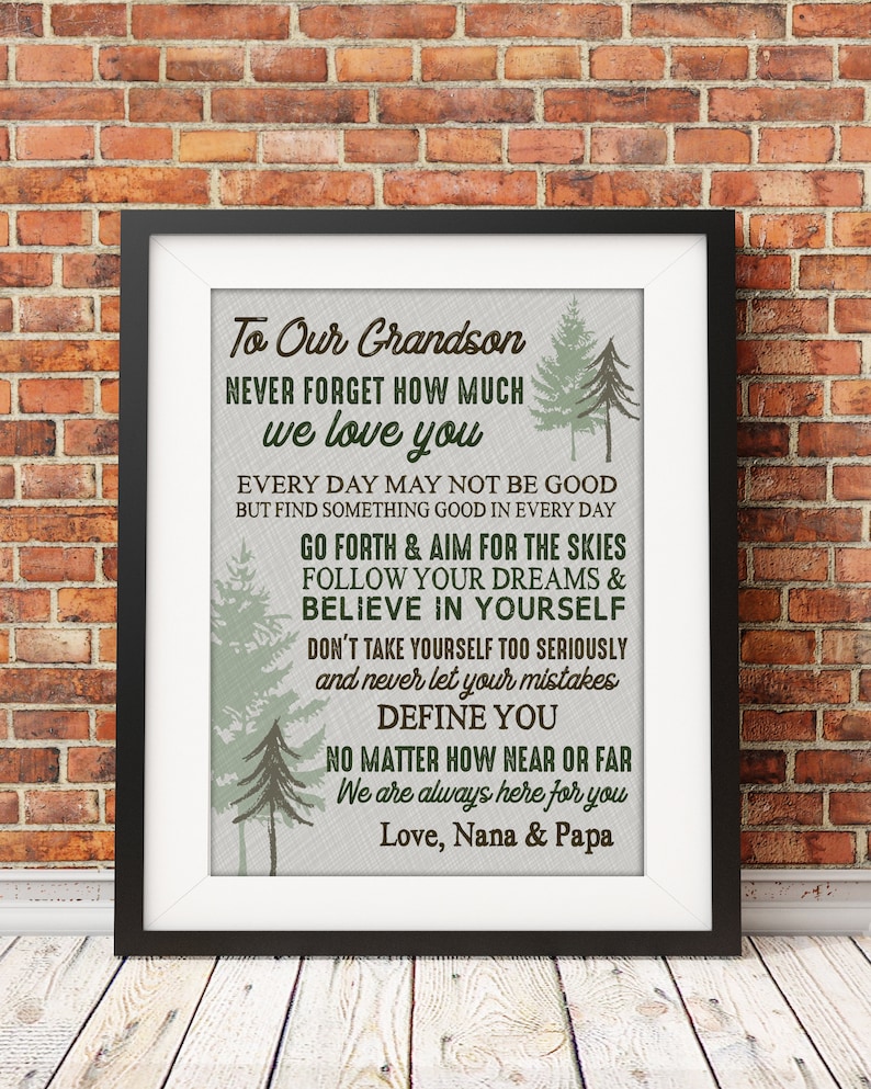 May include: A framed print with a white background and brown text that reads "To Our Grandson Never Forget How Much We Love You" and includes a message about following your dreams and believing in yourself. The print features a green and brown forest design.