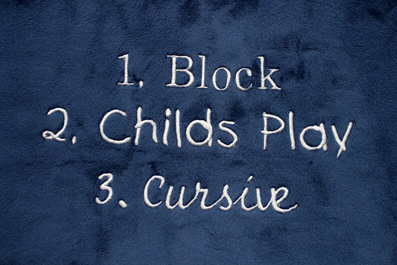 May include: A blue fabric with white embroidered text that reads "1. Block", "2. Childs Play", and "3. Cursive".