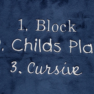May include: A blue fabric surface with white embroidered text that reads "1. Block", "2. Childs Play", and "3. Cursive".