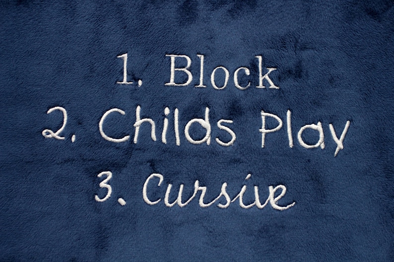May include: A blue fabric surface with white embroidered text that reads "1. Block", "2. Childs Play", and "3. Cursive".