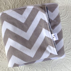 May include: A gray and white chevron patterned baby blanket with a small white tag that says "Handmade with Love".