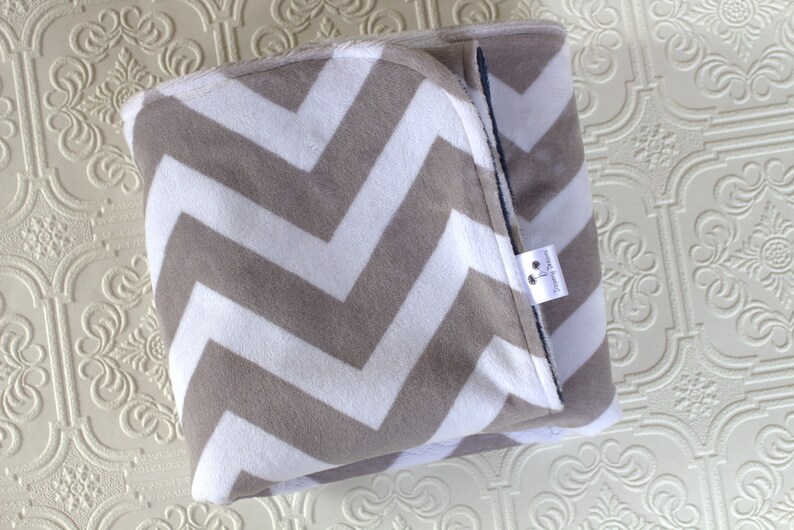 May include: A gray and white chevron patterned baby blanket with a small white tag that says "Handmade with Love".