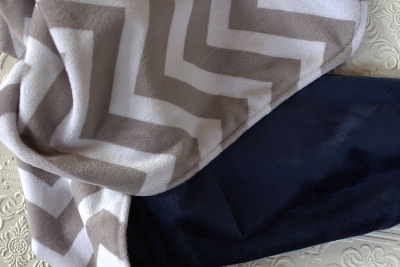 May include: A chevron patterned throw blanket in beige and white with a dark blue backing.