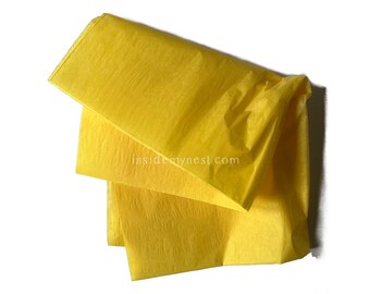 May include: Bright yellow tissue paper sheets, layered and slightly crumpled, against a white background. The paper has a textured appearance, suggesting a delicate, lightweight material. Ideal for gift wrapping or crafting.