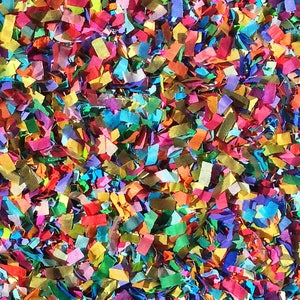 Op de afbeelding: Een close-up afbeelding van kleurrijk confetti, een mix van rode, blauwe, groene, gele en paarse papiertjes. Het confetti is willekeurig verspreid, wat een feestelijke en vrolijke sfeer creëert.