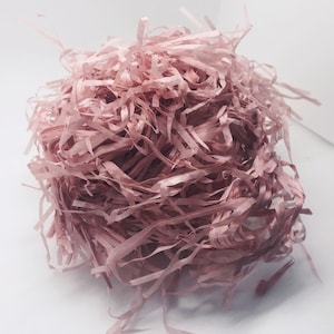 May include: A pile of pink shredded paper, commonly used as packing material or for gift wrapping.