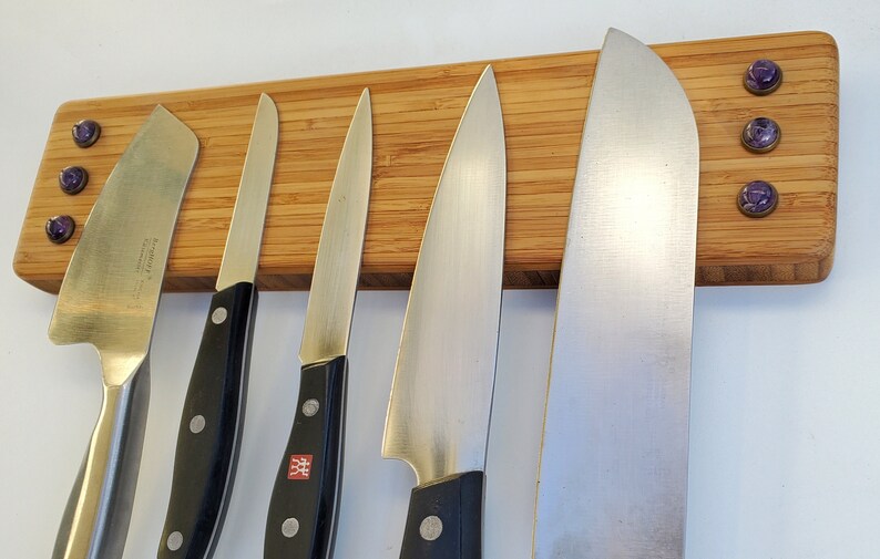 Puede incluir: Un soporte de bamb&uacute; para cuchillos con seis cuchillos de acero inoxidable. El soporte rectangular tiene detalles decorativos morados. Los cuchillos tienen mangos negros y diferentes formas de hoja, aptos para la cocina.