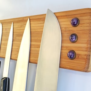 Puede incluir: Un soporte de cuchillos de bamb&uacute; con varios cuchillos de acero inoxidable de diferentes tama&ntilde;os. El soporte tiene tres imanes decorativos de piedras preciosas moradas. El bamb&uacute; es de color marr&oacute;n claro con vetas de madera natural.