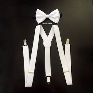 May include: White suspenders with silver clips and a white bow tie. The bow tie has a black elastic band.