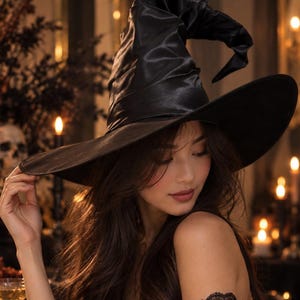 May include: A black witch hat with a wide, slightly drooping brim and a tall, pointed, slouchy crown. The hat is crafted from a smooth, satin-like material that reflects light, creating subtle highlights across its curved, structured surface.