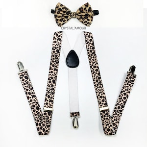 May include: A set of brown and black leopard print suspenders with silver clips and a matching bow tie. The suspenders have a white elastic band in the back. The bow tie has a black elastic band.