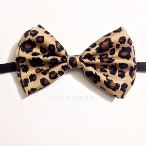 May include: A brown and black leopard print bow tie with an elastic band.