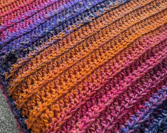 May include: A multi-colored crochet blanket with stripes of orange, pink, purple, and blue.