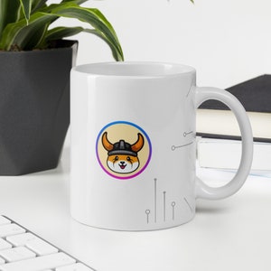 Pu&ograve; includere: Tazza in ceramica bianca con un'immagine di un cartone animato di una volpe che indossa un casco e un design circolare giallo, arancione, viola e blu. La tazza ha un manico bianco e uno sfondo bianco con un design a circuito grigio.