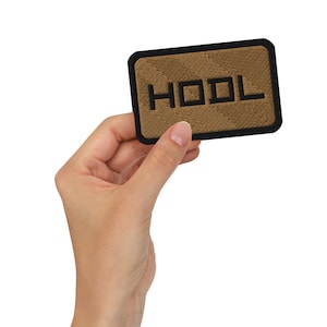 May include: A brown fabric patch with black stitching and the word "HOOL" in black lettering.