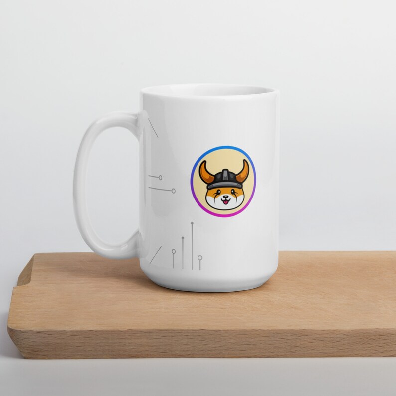 Pu&ograve; includere: Tazza in ceramica bianca con un'immagine di un cane di cartone animato che indossa un elmo vichingo. Il cane &egrave; arancione e bianco con un elmo nero. L'immagine &egrave; circondata da un cerchio con un contorno blu e viola. La tazza ha un manico nero e si trova su una superficie di legno.