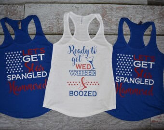 May include: Two blue racerback tank tops with white stars and the text LET'S GET STAR SPANGLED HAMMERED in red and white, and one white racerback tank top with the text Ready to get WED WHITE & BOOZED in blue and red with a martini glass.