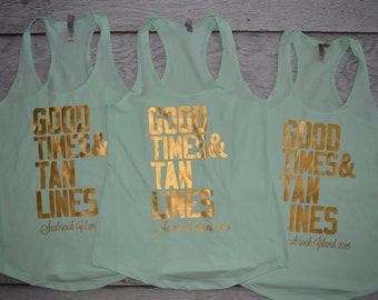 May include: Three light mint green racerback tank tops featuring metallic gold lettering that reads GOOD TIMES & TAN LINES and Seabrook Island 2016. The sleeveless shirts have a scoop neckline and a lightweight, solid-colored fabric construction.
