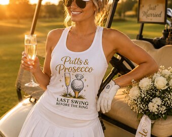 May include: A white tank top featuring gold text that reads Putts & Prosecco and Last Swing Before The Ring, with a graphic of a champagne flute and a golf ball on a tee with a diamond ring on top, paired with a white pleated skirt and a white visor.