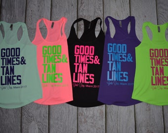 May include: Five racerback tank tops in mint, neon pink, black, purple, and lime green. Each features the text GOOD TIMES & TAN LINES and Girls Trip, Miami 2017 in contrasting colors printed on the front of the sleeveless garments.