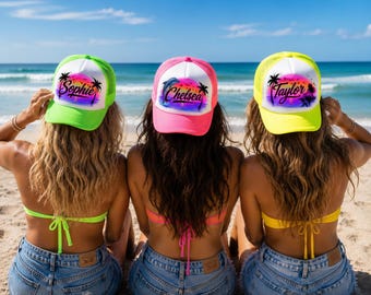 May include: Three trucker hats featuring a white front panel with a colorful sunset, palm tree, and dolphin graphic. The left hat is neon green, the center is neon pink, and the right is neon yellow. Each hat displays a name: Sophie, Chelsea, or Taylor.