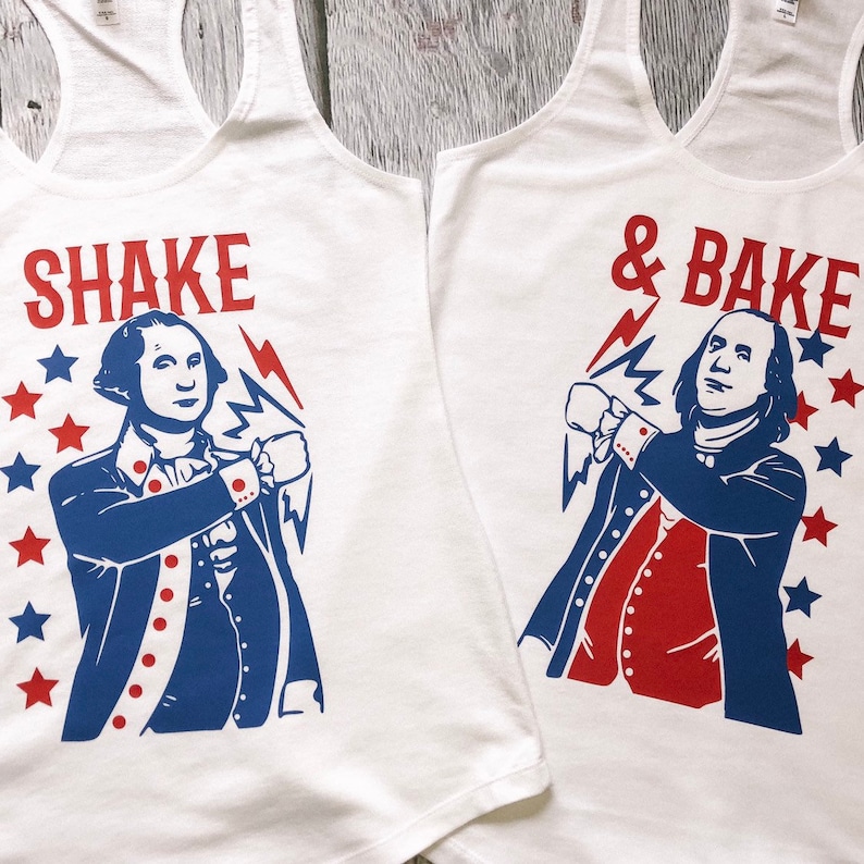 May include: Two white tank tops with a red, white and blue graphic design. One tank top says "SHAKE" and features a cartoon image of a man with a lightning bolt. The other tank top says "& BAKE" and features a cartoon image of a man with a lightning bolt.