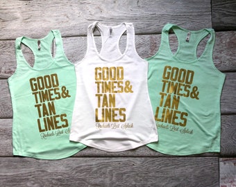 May include: Three racerback tank tops, two in light mint green and one in white, each featuring the gold metallic text GOOD TIMES & TAN LINES and the script text Rachael's Last Splash printed on the front chest area.
