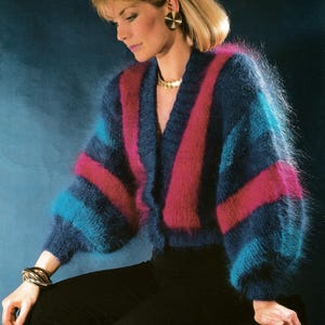 May include: A vintage mohair cardigan in blue, pink, and turquoise stripes. The cropped sweater has a V-neck and long sleeves. The image includes the text "Nocturne" and "Gold Seal Luxury Mohair".