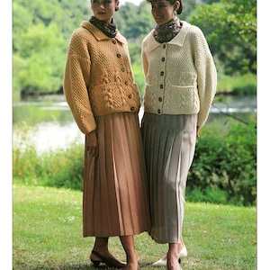 Puede incluir: Imagen de moda con dos mujeres que lucen cárdigans de punto y faldas plisadas. Un cárdigan es amarillo mostaza, el otro crema. El texto "SIRDAR HIGHLANDER Chunky" y "SIRDAR" son visibles.