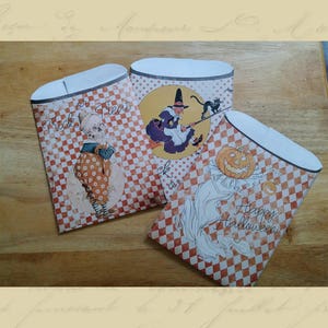May include: Three orange and white checkered paper treat bags with Halloween themes. One bag features a witch flying on a broomstick with a black cat, another bag features a girl in a dress holding a pumpkin, and the third bag features a ghost with the text "Happy Halloween".