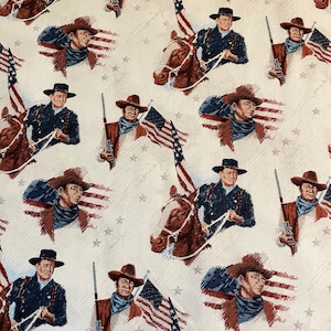 May include: A white fabric with a repeating pattern of a cowboy riding a horse, holding an American flag, and a signature. The cowboy is wearing a blue shirt, brown hat, and jeans. The horse is brown and white.