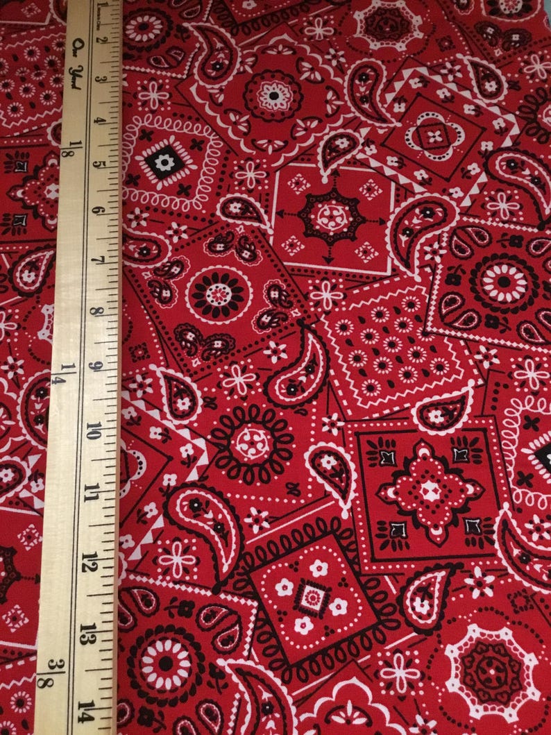 May include: Red fabric with a paisley pattern. The fabric is covered in a repeating pattern of red, white, and black paisley shapes.