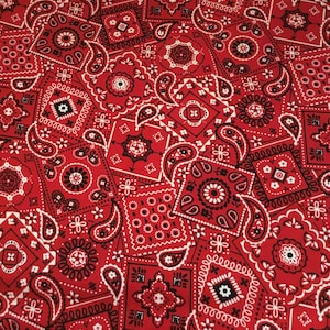 May include: Red and white bandana print fabric with a paisley pattern. The fabric is made of cotton and is ideal for quilting, crafts, and other projects.