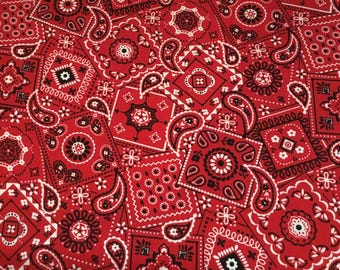 May include: Red and white bandana print fabric with a paisley pattern. The fabric is made of cotton and is perfect for quilting, crafts, and other projects.