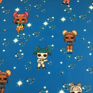 May include: Blue fabric featuring repeating patterns of cartoon dolls, hearts, and starbursts. The dolls have large eyes and various hairstyles. The text "OMGA" is visible on some dolls. The hearts are a darker shade of blue.