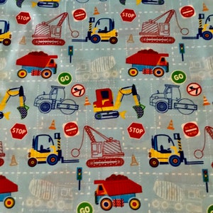 May include: A blue fabric with a repeating pattern of construction vehicles, traffic signs, and cones. The vehicles include a yellow forklift, a red dump truck, a gray cement mixer, a red excavator, and a gray road roller. The traffic signs include a red stop sign, a green go sign, and a white do not enter sign.