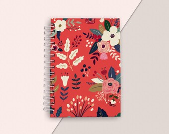 May include: A red spiral notebook with a floral pattern. The flowers are white, pink, and red with green leaves and stems.