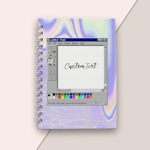 Peut inclure: Un carnet à spirales avec une couverture holographique représentant un écran d'ordinateur vintage affichant le texte "Custom Text" dans un programme de peinture. L'écran comprend une palette de couleurs et le texte "Pour obtenir de l'aide, cliquez sur Rubriques d'aide dans le menu Aide."