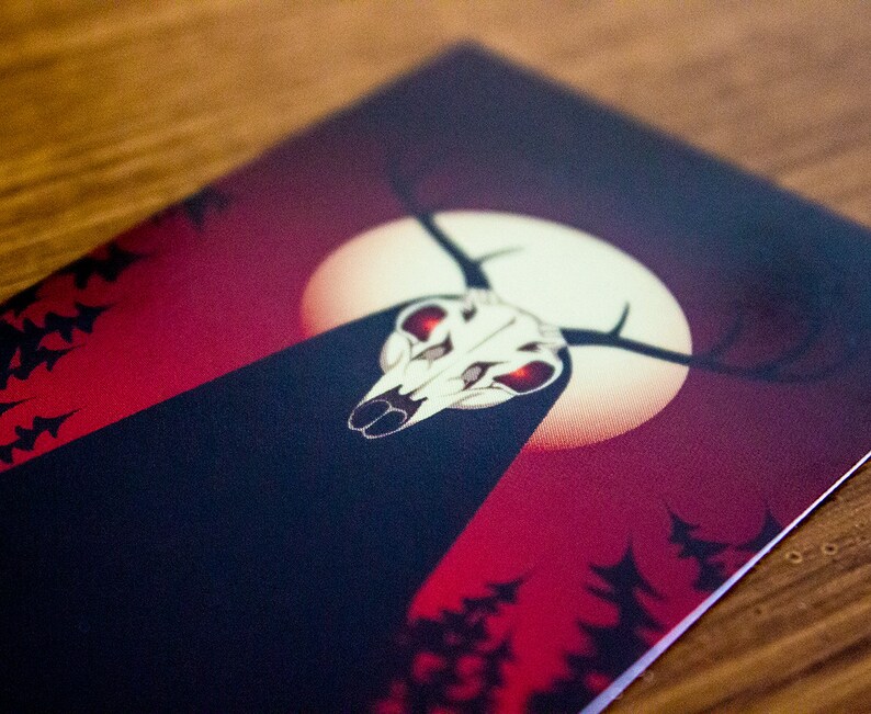 May include: A dark red and black card featuring a white skull with red eyes and antlers. The skull is positioned in front of a white moon against a red backdrop. The card has a dark forest silhouette in the background.
