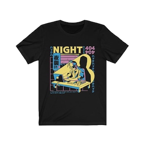 以下が含まれることがあります： 「NIGHT 404 HACK」と日本語の文字が書かれた、レトロなスタイルのラップトップで作業している人のグラフィックが描かれた黒いTシャツ。