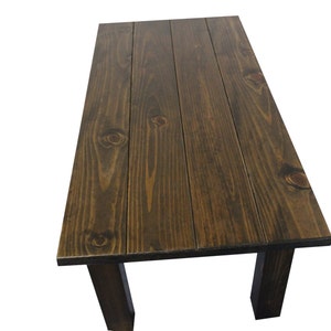 Puede incluir: Una mesa de madera marr&oacute;n oscuro con una tapa rectangular y cuatro patas. La tapa de la mesa est&aacute; hecha de tablones de madera.